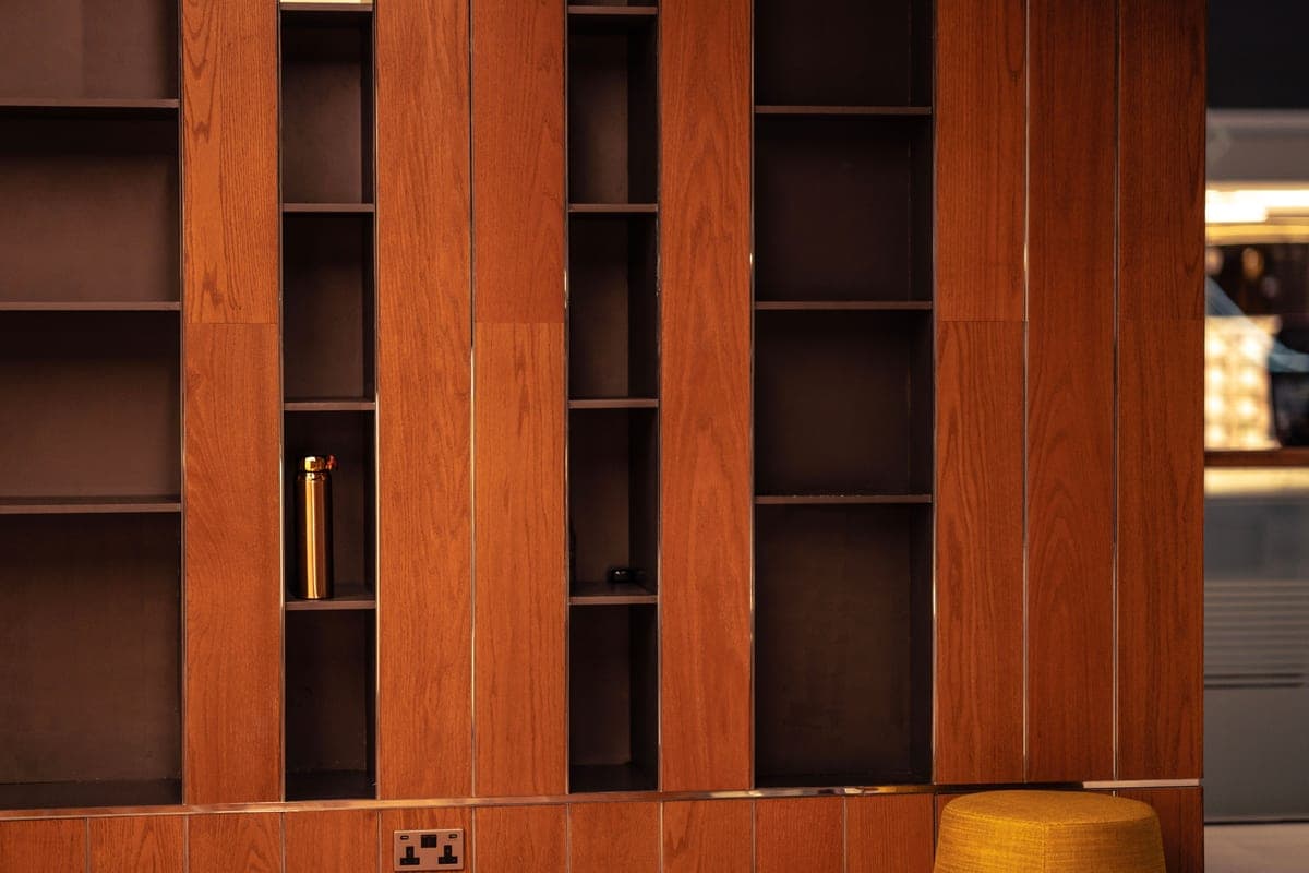 A black metal shelving unit with glass shelves in a dimly lit room